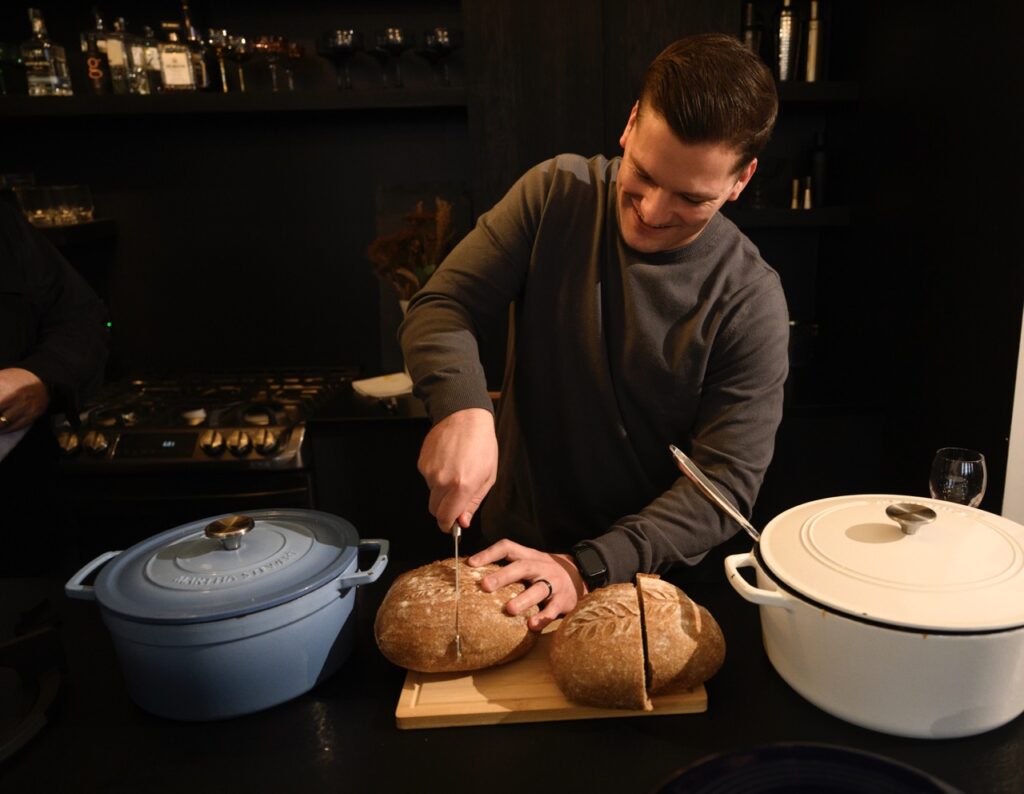 A man cuts into a round loaf of bread.