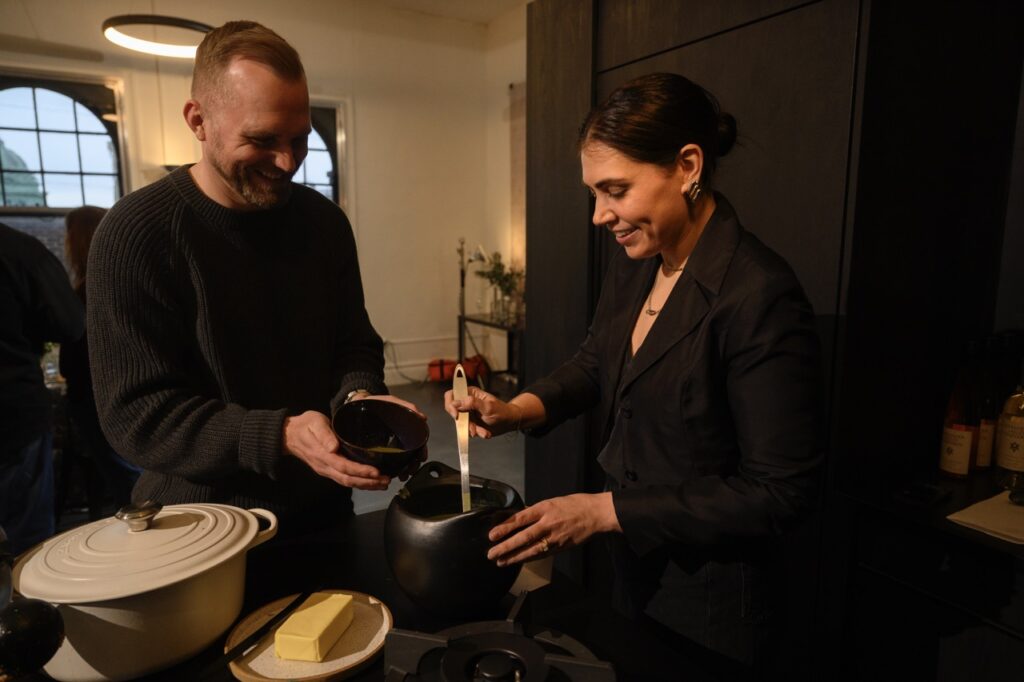 A woman dishes out soup for a man.
