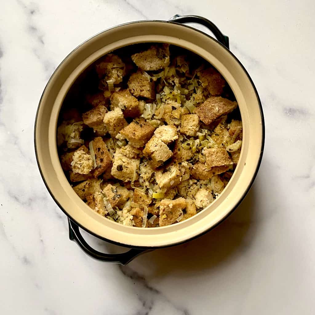A pot filled with bread stuffing on a white marble tabletop.