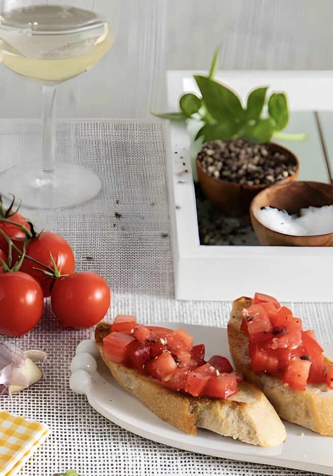 Bruschetta on a plate beside some heirloom tomatoes