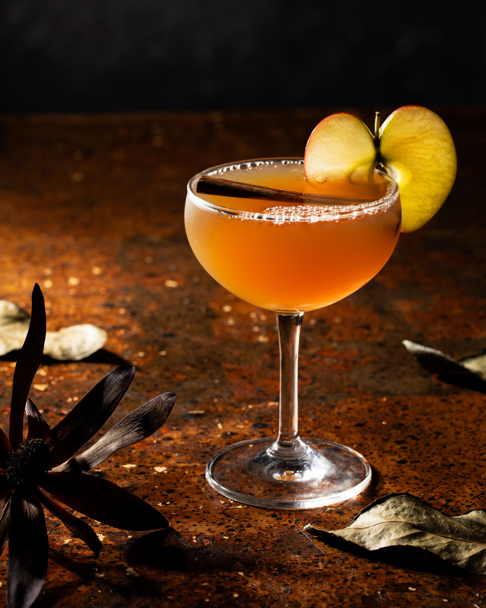 A Thankgiving dinner table set with a mocktail garnished with apple