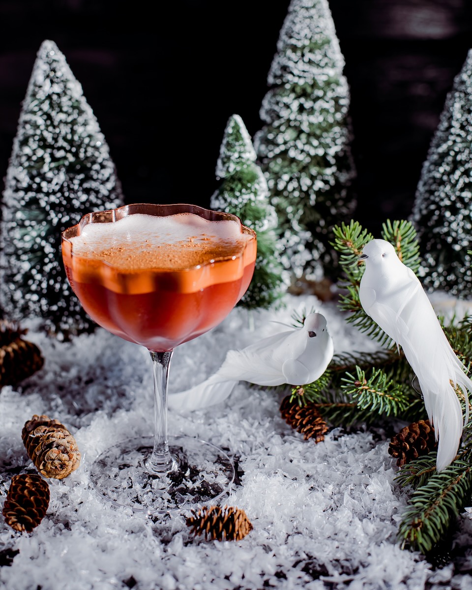 A Christmas cocktail with tequila and mezcal staged with two fake birds representing the two turtle doves in the song "Twelve Days of Christmas"