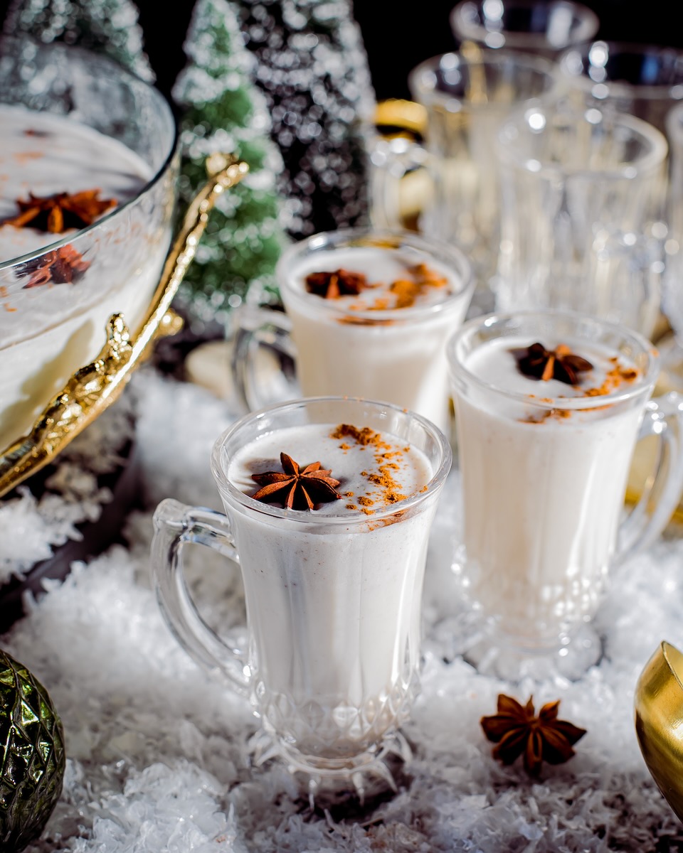 A set of festive coquito cocktail glasses staged on a holiday-themed table