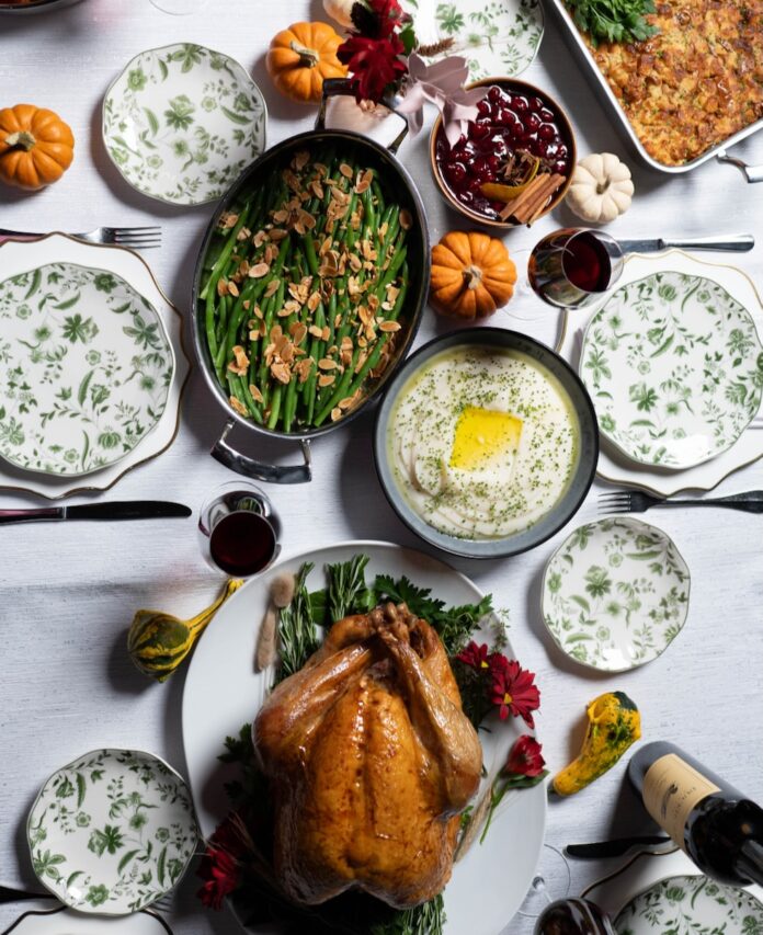 A spread of Thanksgiving dinner like a turkey, green beans, mashed potatoes, casserole, and more.