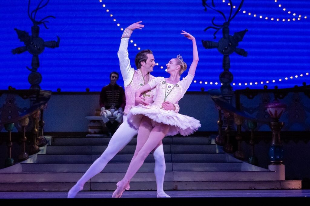 A couple in pink doing ballet on stage for The Nutcracker.