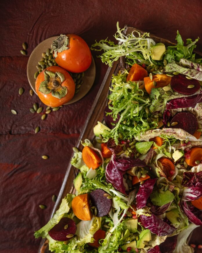 Winter Chicories Salad with Persimmons and Avocado Colorful salad with tomatoes on side