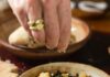 Winter Greens Minestrone Soup Hand drizzling cheese onto a dish
