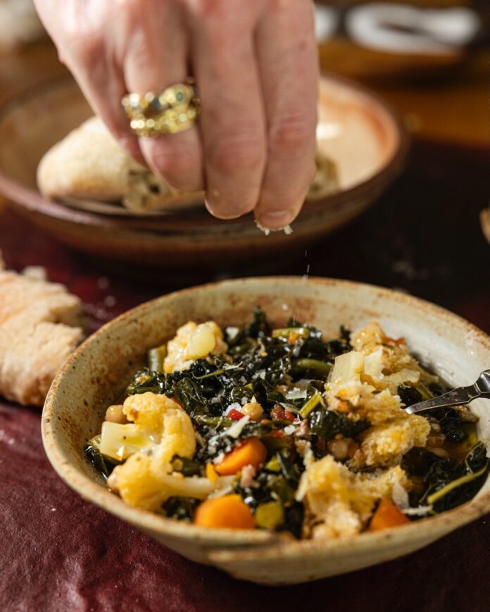Minestrone Hand drizzling cheese onto a dish