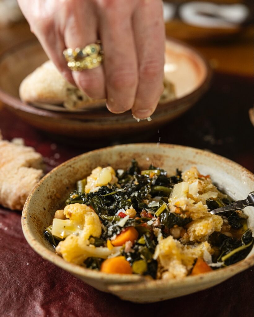 Hand drizzling cheese onto a dish