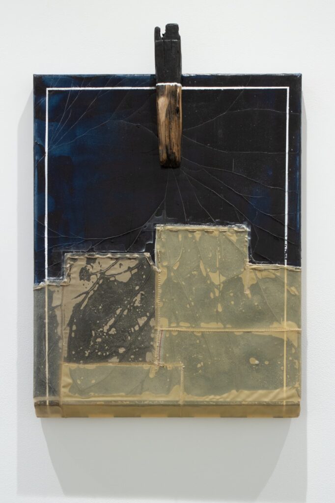 A black and patchwork painting by Justin Emmanuel Dumas on a wall.