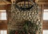A Luxurious Wade Weissmann-Designed Addition in Fox Chapel A woman decorates a stone fireplace with a large green wreath.