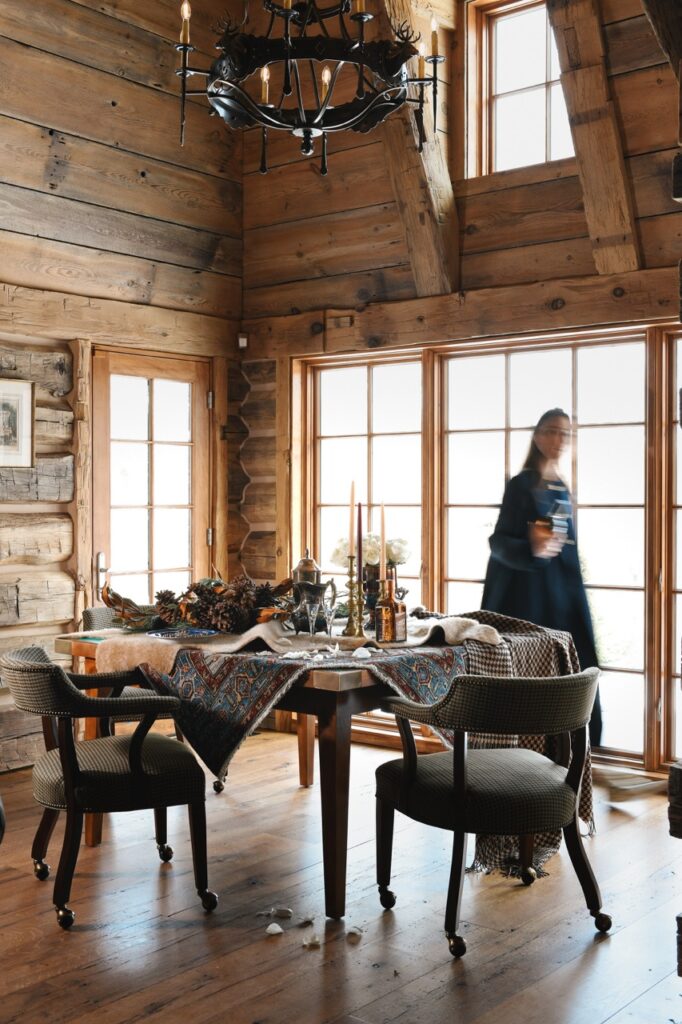 A woman sets a table in what looks like a wood cabin.