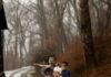 Channel ‘Where the Wild Things Are’ for Winter Birthdays Parties A line of young children dressed in pajamas and animal masks walking down a snowy, muddy path in the woods, with the boy in front wearing a crown and striped pajamas.