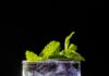 Wicked: For Good, A Magical Cocktail A Wicked: For Good cocktail sits on a black table with mint leaves for garnish.