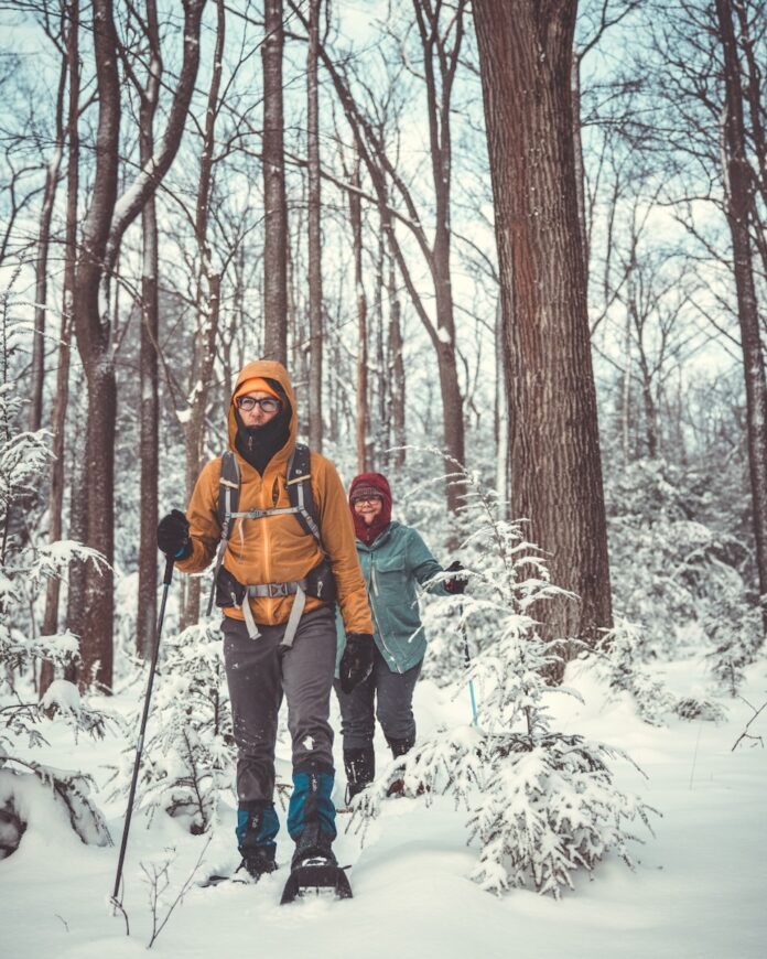 A man and his daughter hiking through a snowy forest.