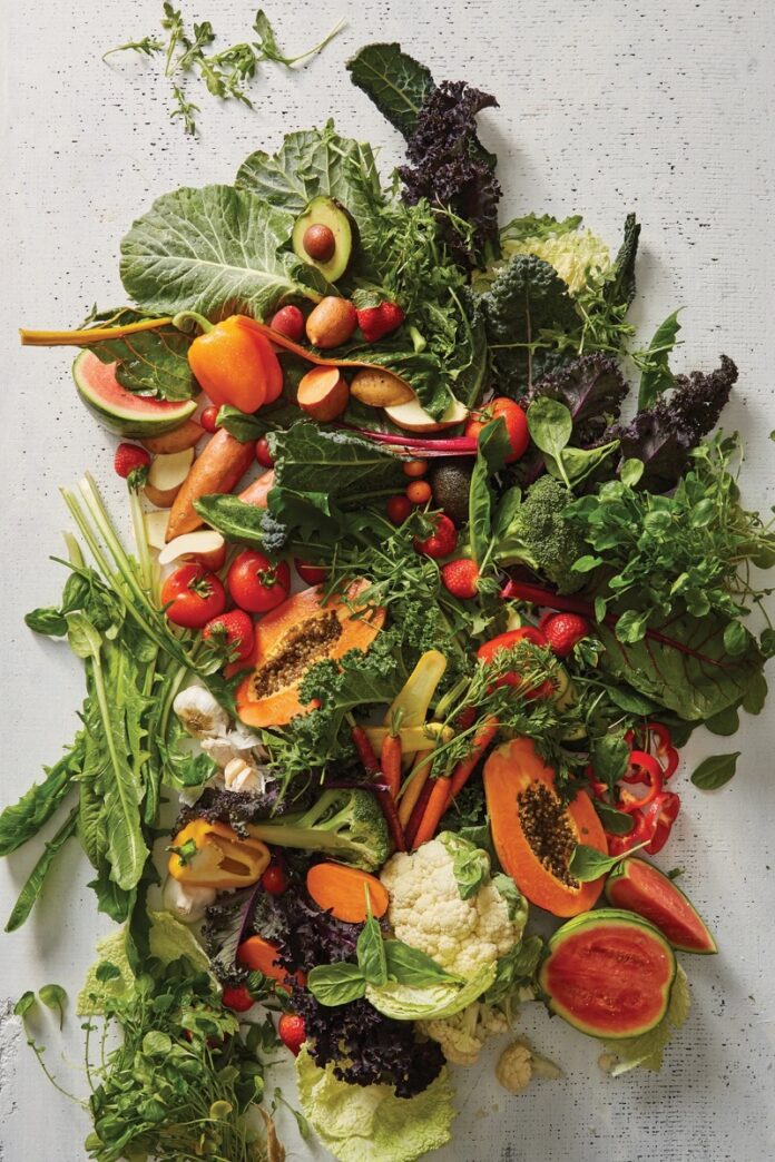 Bright Ideas TABLE Magazine A variety of colorful and fresh produce, including papaya, strawberries, avocados, tomatoes, broccoli, peppers, cauliflower, and leafy greens, promoting skin health.