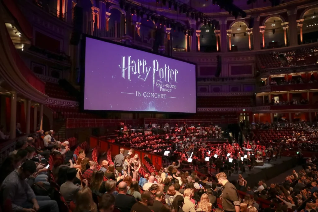 A screen plays Harry Potter above a live orchestra below.