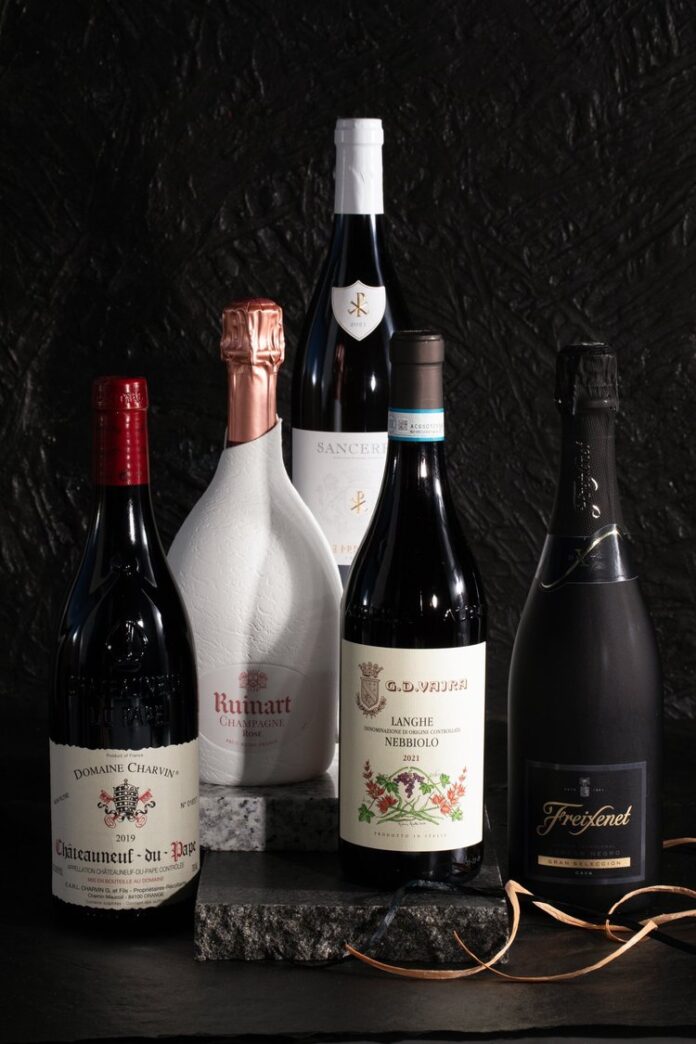 Five bottles of wine stacked on a table for gifting.