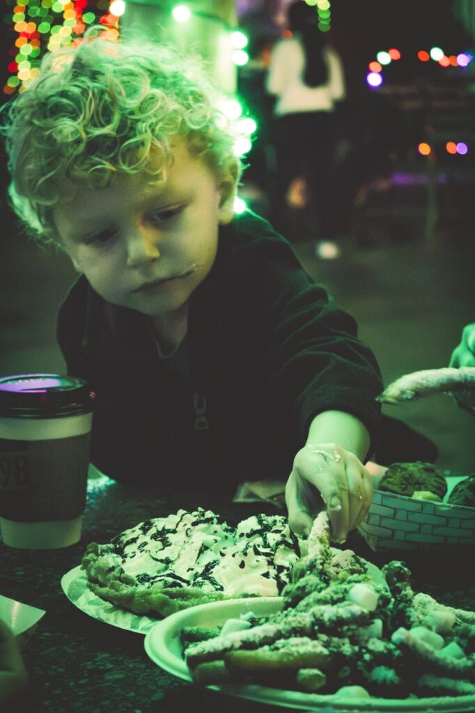 A little boy grabs a funnel cake fry.