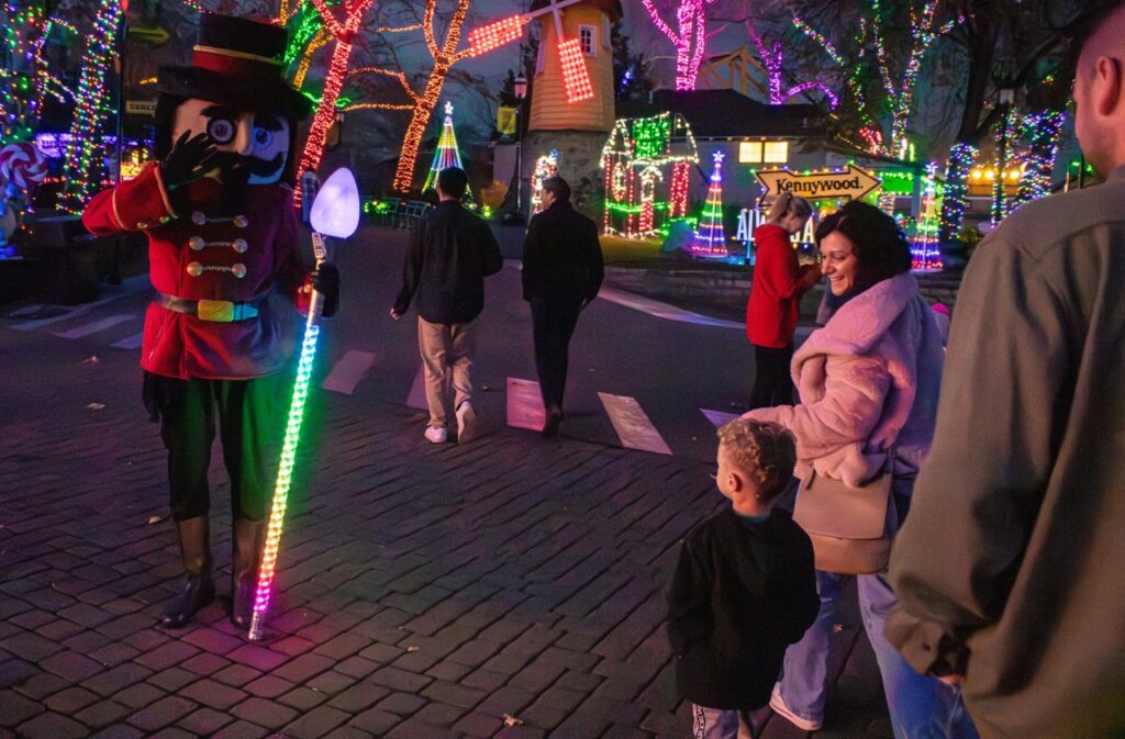 A nutcracker character waves at a little boy.