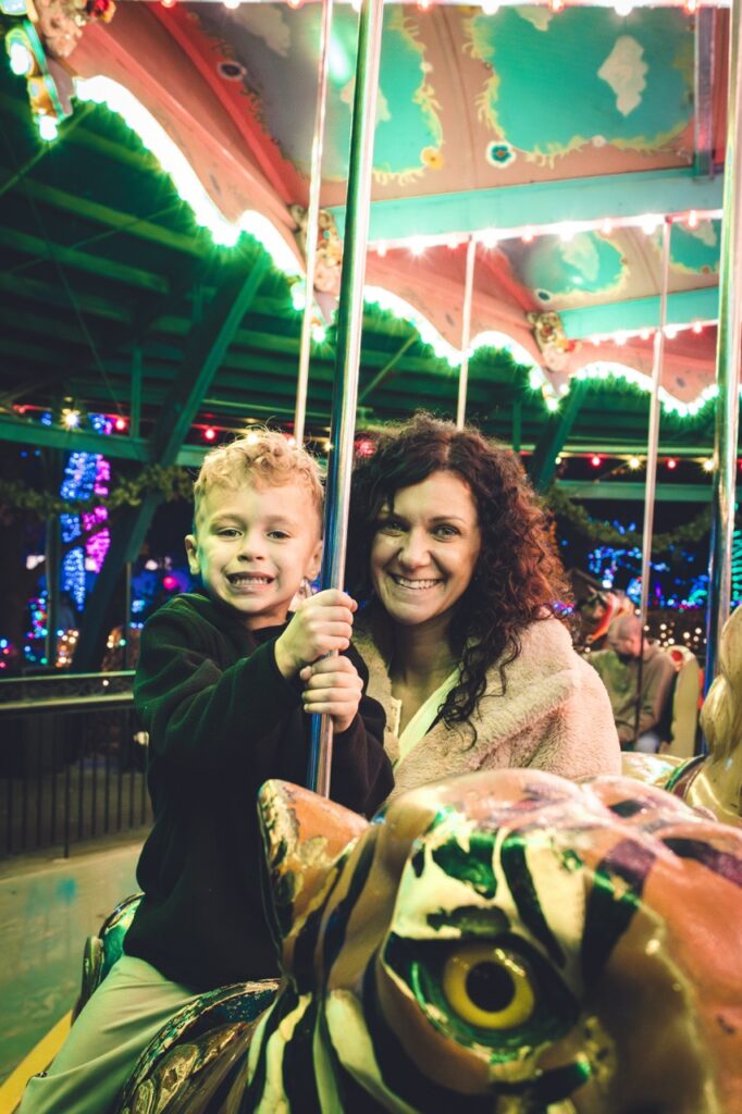 A boy and his mom smile on the carousel.