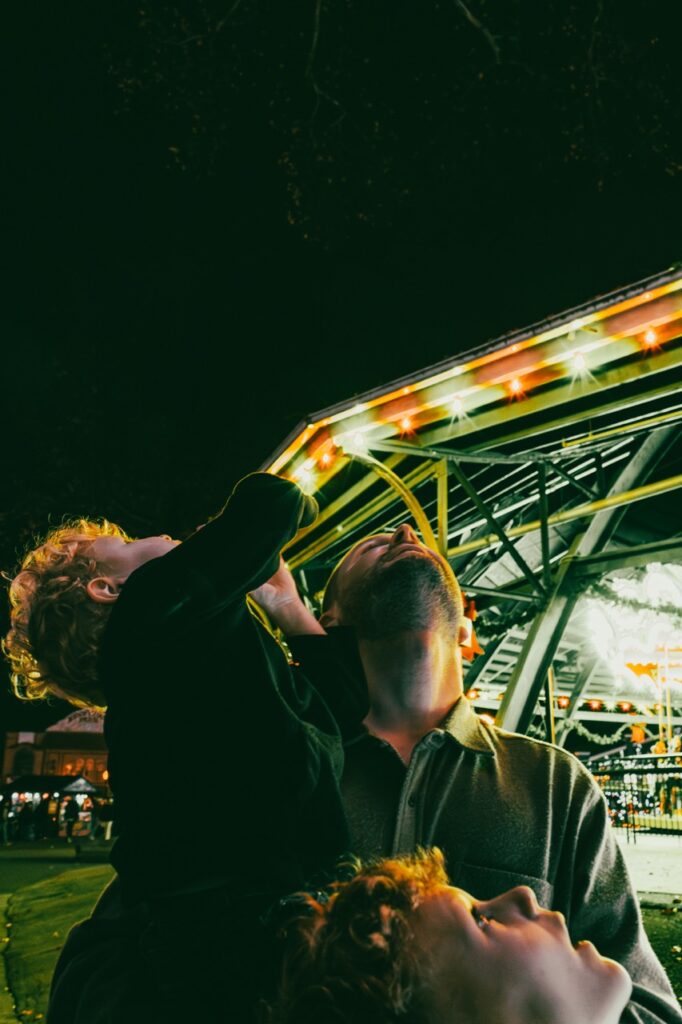 A dad and two sons look up at the sky.