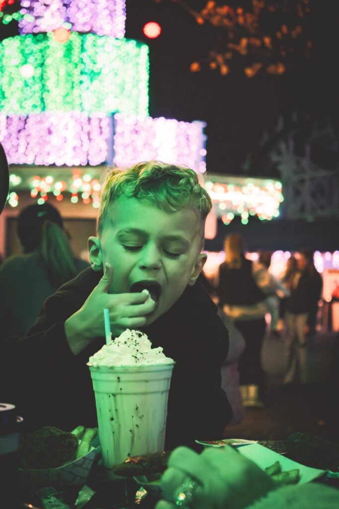 A boy licks whipped cream off his finger.