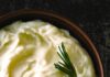 We Taste Tested 5 Mashed Potato Recipes from Celebrity Chefs to Find the Best A bowl full of creamy mashed potatoes with a sprig of thyme in it.