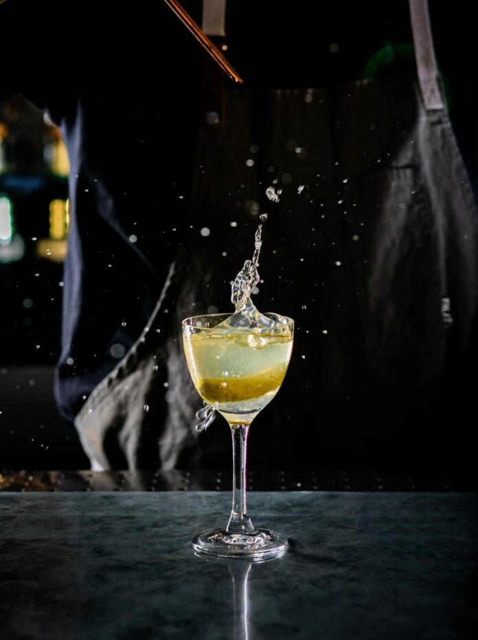 A bartender splashed a drop of liquid into a cocktail glass.