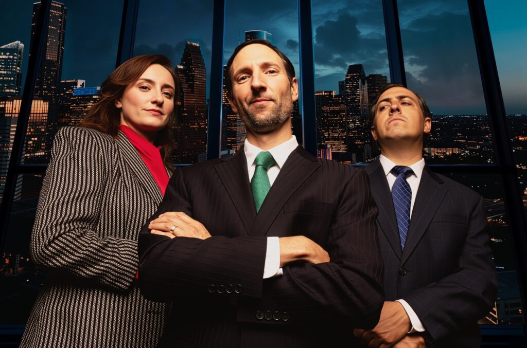 Two men and a woman in suits standing in front of a window.