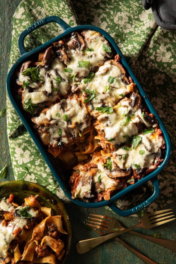 A pan of Wild Boar Pappardelle with a plate of a slice beside it.