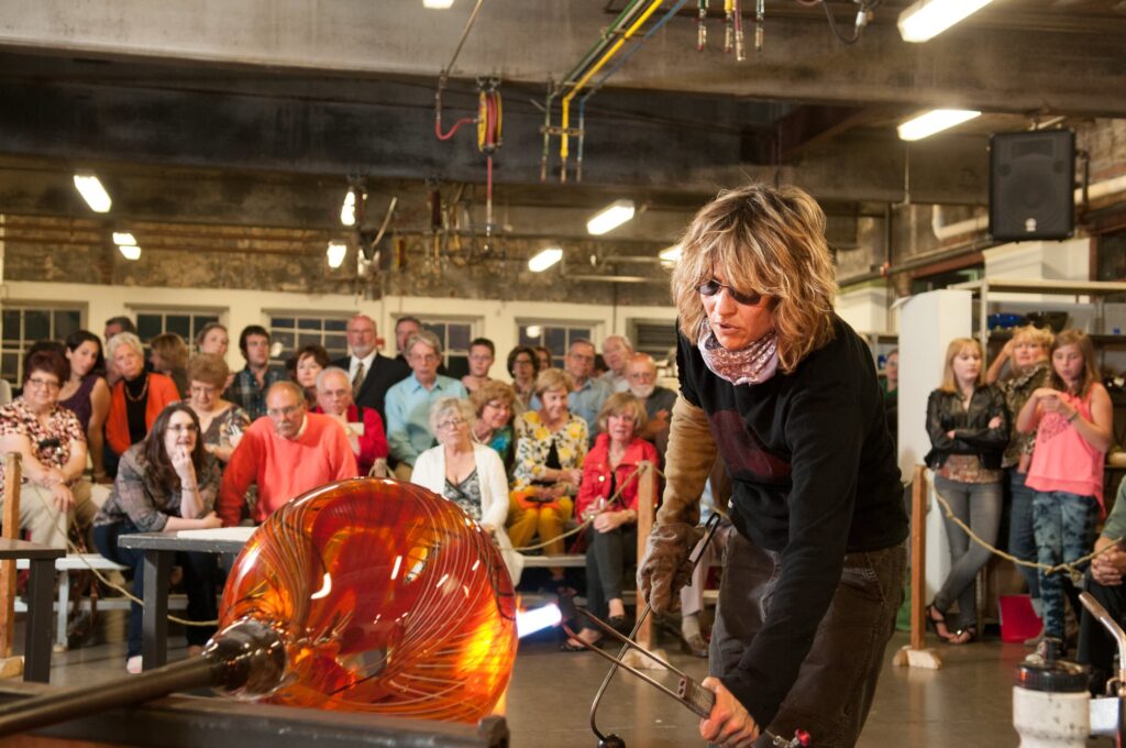 HOT Jam – 25 Years and Still Glowing! people watching a woman blow glass