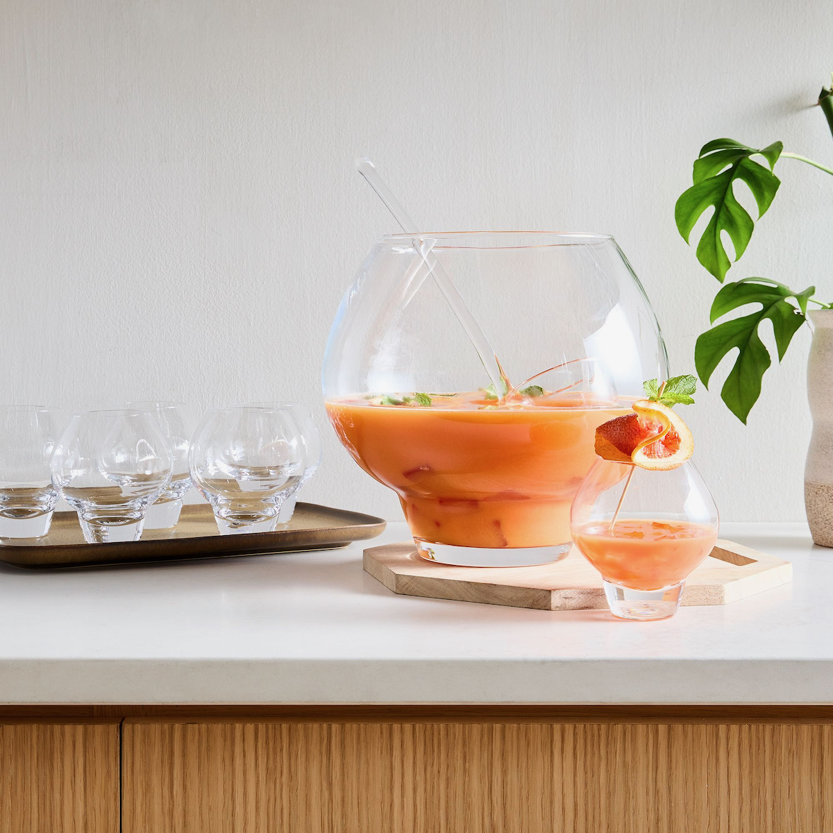A punch bowl from West Elm with orange liquid in it staged on a table