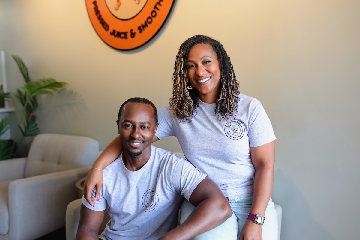 A man sits on a chair as a woman sits on the side of the chair beside him. 