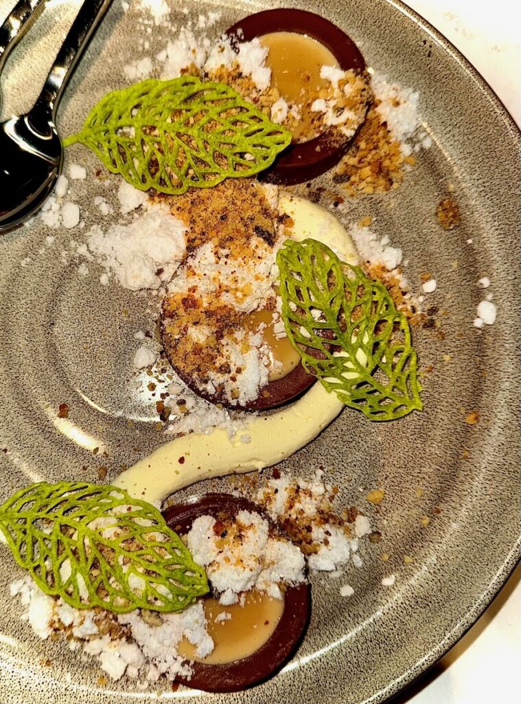 Small chocolates with a butterscotch filling sit with pistachio leaves on top.