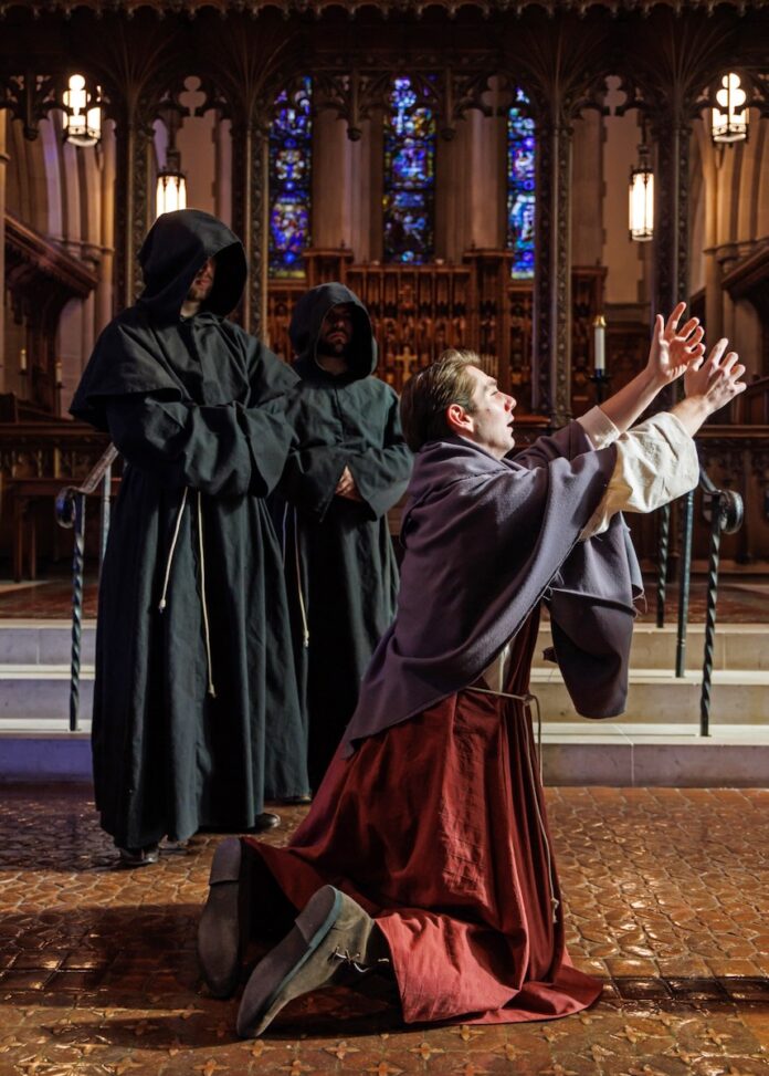 A man falls to his knees in front of two hooded figures.