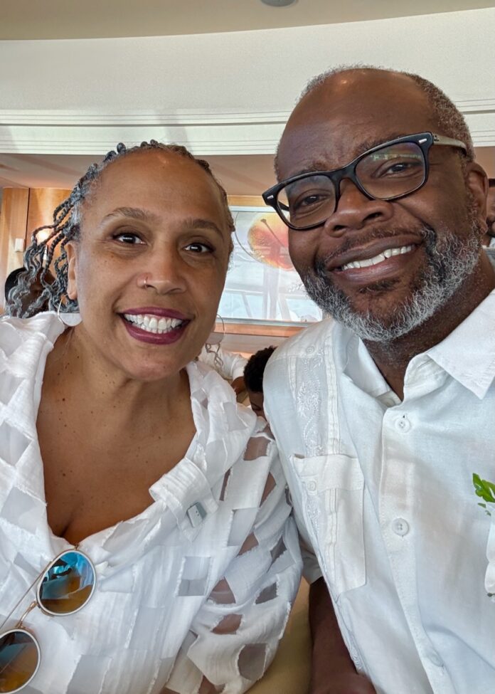 Cynthia and John Wallace together in white outfits with smiles on their faces.