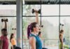 Pittsburgh Fitness Classes in January 2026 A woman coaches a fitness class while lifting weights and lunging.