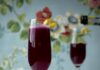 Throw a Colorful Cocktail Watch Party for the Premiere of ‘Bridgerton’ Season Four Two champagne flutes of a dark purple Lord & Lady Bridgerton cocktail with a lemon peel twist garnish, butterfly pea flowers below, and a bottle of champagne pouring into the background glass. It's all set against a blue floral background.