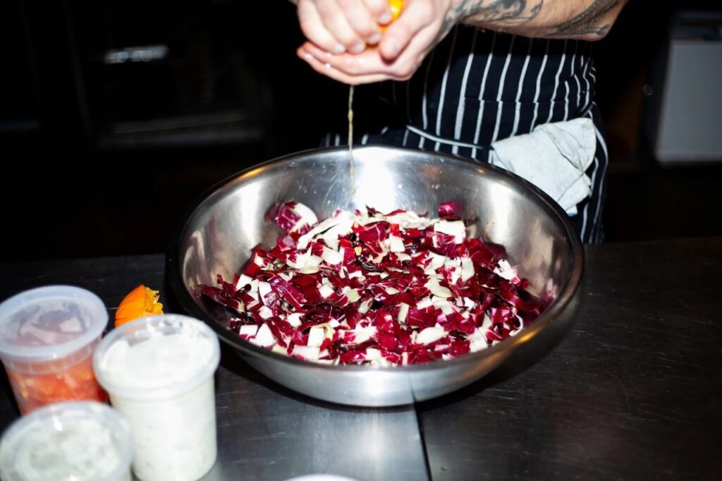 A chef squeezes juice into sliced red cabbage.