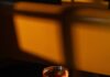 Naked in Manhattan Cocktail for Chappell Roan A cocktail in am amber color sits in a tall glass on a table in the evening light.