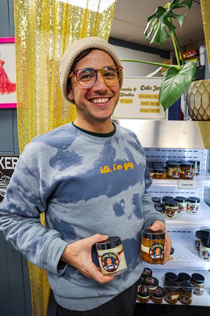 A man holds two small cake jars.