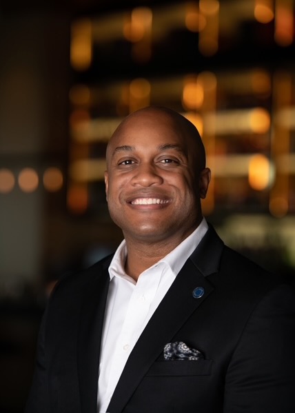 A man stands in a white shirt and black jacket.