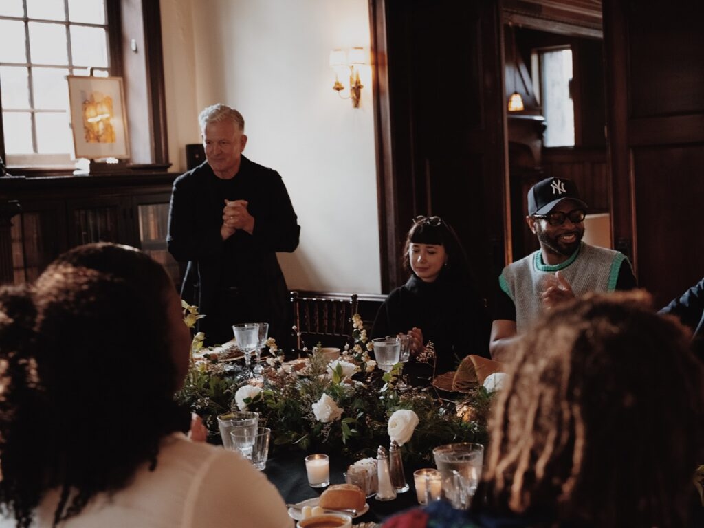 A man speaks to a dining table of people.