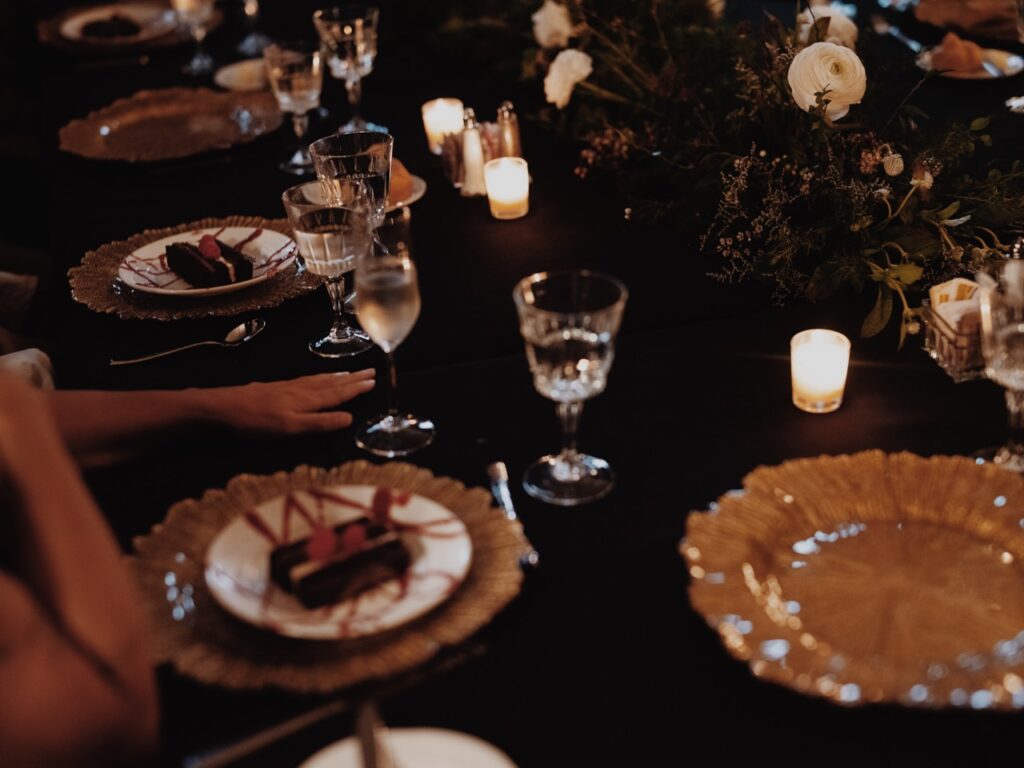 Gold plate place settings with white dessert plates on top of them.