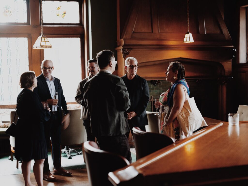 A group of men and women speak in a large open room.