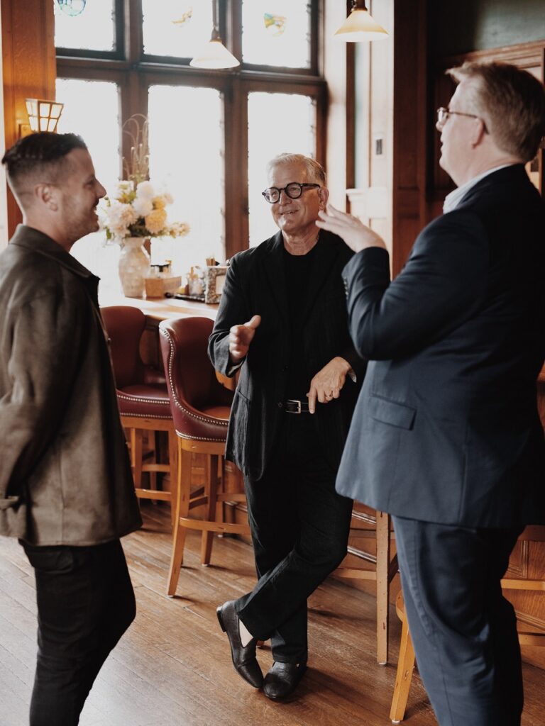 Three men talk together.