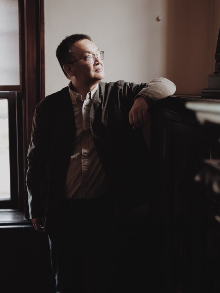 A man leans his arm on a railing and looks over it.