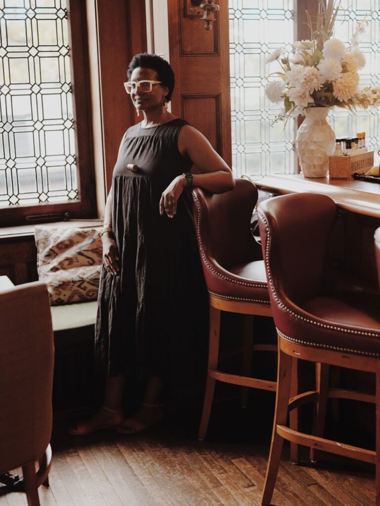 A woman leans back against a tall chair.