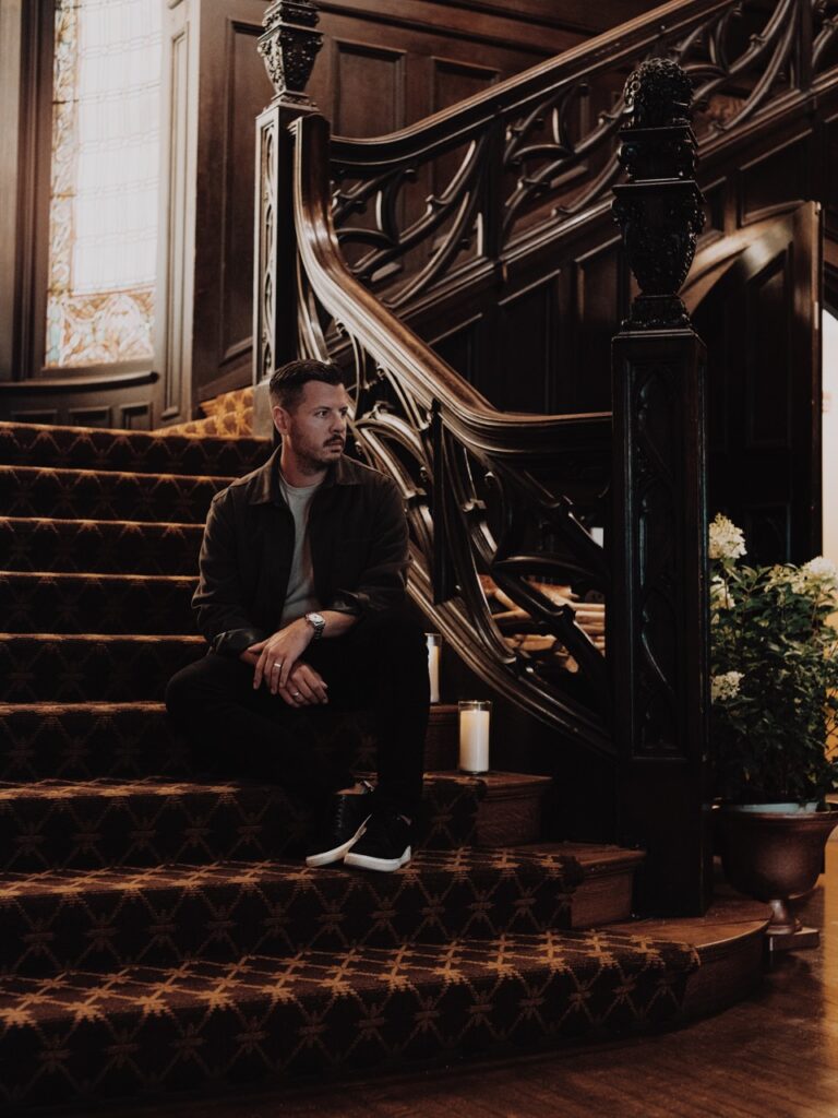 A man sits on a staircase with his hands on his knees.